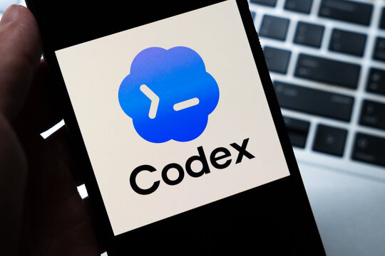 Warsaw, Poland - July 26, 2026: Codex AI coding assistant logo displayed on smartphone screen held in hand against laptop keyboard background