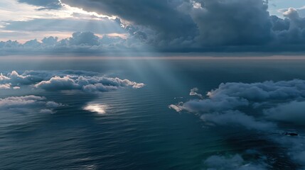 Fototapeta premium Rays of light shine through clouds over the sea during sunset