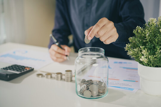 Savings investment planning with business professional placing a coin into money jar to build emergency funds strengthen financial discipline manage budgets and achieve long term wealth goals.