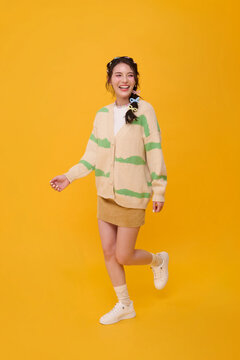 Asian woman smiling and posing on one leg in studio expressing youthful confidence cheerful lifestyle positive energy fashion appeal and playful individuality with copy space.