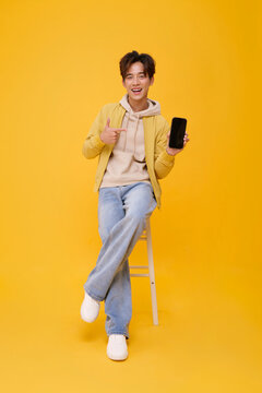 Smartphone mockup with smiling Asian man pointing at blank screen in studio promoting mobile apps digital services online communication advertising and confident technology lifestyle.