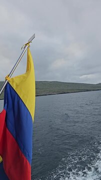 Ecuador flag waving with wind currents on back of boat on the ocean vertical video