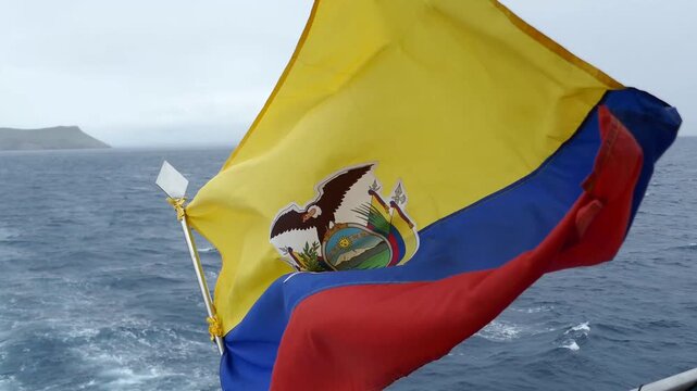 National Flag of Ecuador waving rapidly in wind on back of ship with ocean wake flowing in background