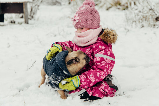Child plays with dog in snow-covered yard
