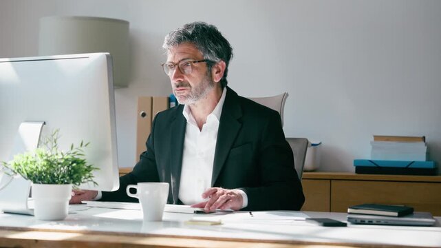 Video of concentrated elegant businessman working on a computer in the office
