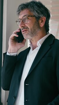 Video of elegant businessman talking with smartphone standing  at the office.