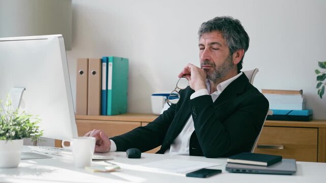 Video of concentrated elegant businessman working on a computer in the office