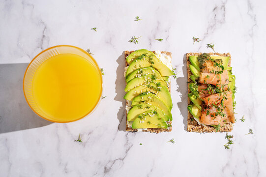 Top view of two healthy avocado and salmon crispbreads with orange juice.