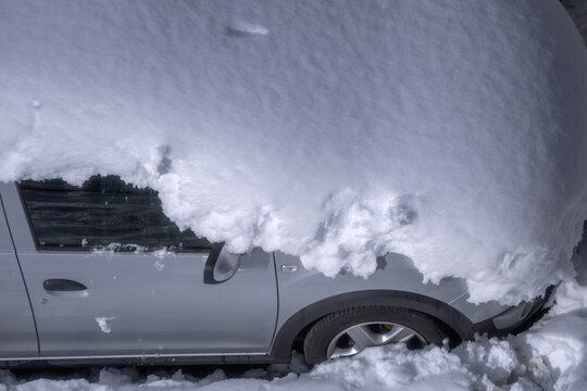 Parked car completely covered by thick layer of snow after a heavy winter snowfall