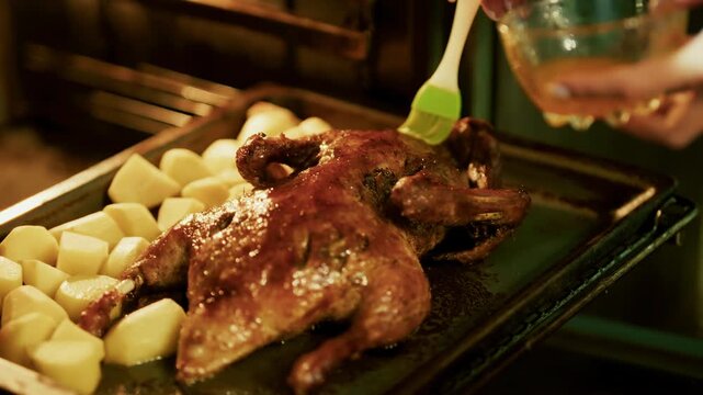 Glazing Roasted Whole Duck With Oil Brush On Baking Sheet With Cut Potatoes In Oven. Poultry Cooking 