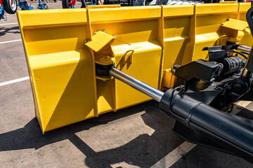 Yellow wheel loader heavy duty dozer blade mechanism. Modern construction machinery steel snow plow push frame section with hydraulic cylinder tilt and industrial vehicle engineering details. © NastyaPhoto
