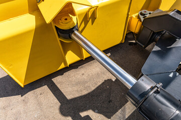 Yellow wheel loader heavy duty dozer blade mechanism. Modern construction machinery steel snow plow push frame section with hydraulic cylinder tilt and industrial vehicle engineering details. © NastyaPhoto