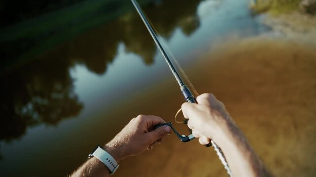 Fisherman Holding Spinning Rod Reeling Fishing Line On Calm River. Shore Outdoor Activity And Hobby. Angler Equipment 