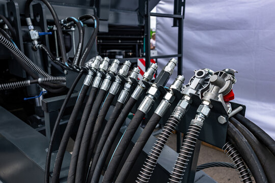 Agricultural machinery hydraulic lines hose quick couplers block. Modern farm equipment pressure hose distribution system on grey chassis frame with industrial vehicle technical details view.