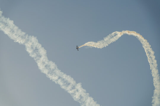 Biplane performing aerobatic maneuvers with smoke trails