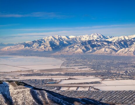 snow capped rocky mountains tower above frozen lakes and valleys with wintry landscapes of provo farmington bountiful orem and salt lake city stretching towards the horizon