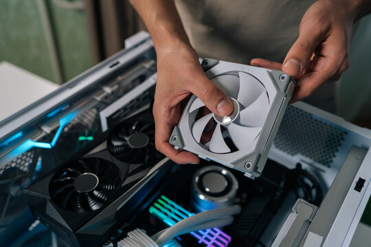 Gaming pc building and upgrading, person installing new cooling fan inside a desktop computer case with rgb lighting, working on hardware for high performance.