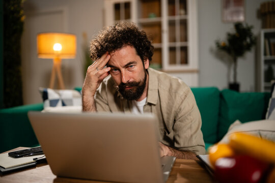 Man working late, feeling stressed and burnout at home