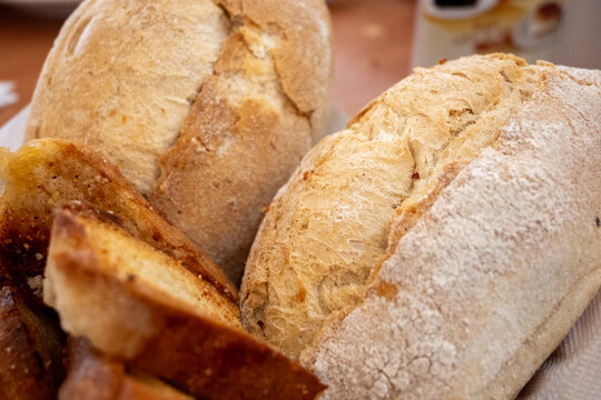 Close-up of fresh artisanal crusty bread rolls and golden toast slices served on a dining table.