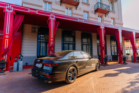 Black Audi A8 parked in front of a luxury hotel with red drapes and elegant architecture in Como, Lombardy, Italy