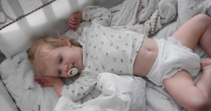 Child resting awake in crib under natural daylight. Toddler sleep routine and early childhood development