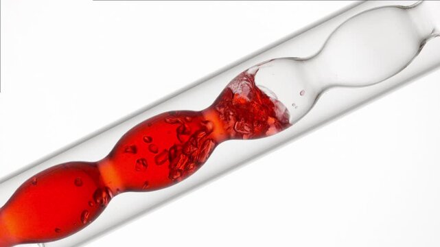 Air bubbles burst through red transparent liquid, filling and draining from a bulb lab condenser on neutral white surface | Hibiscus flower infusion cosmetic formulation concept