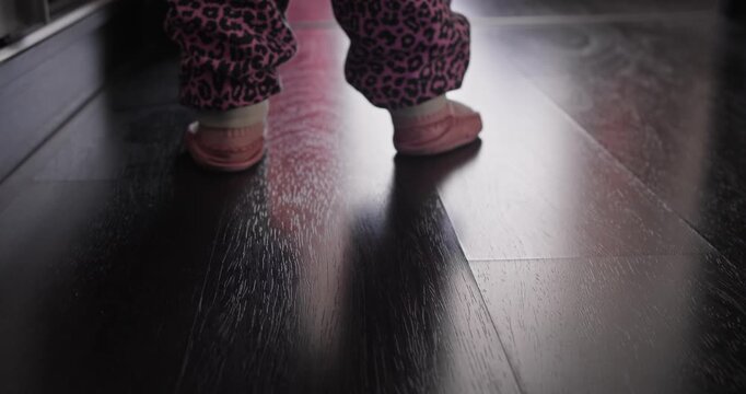 Close-up of toddler feet during early walking practice at home. First steps milestone and balance development in childhood