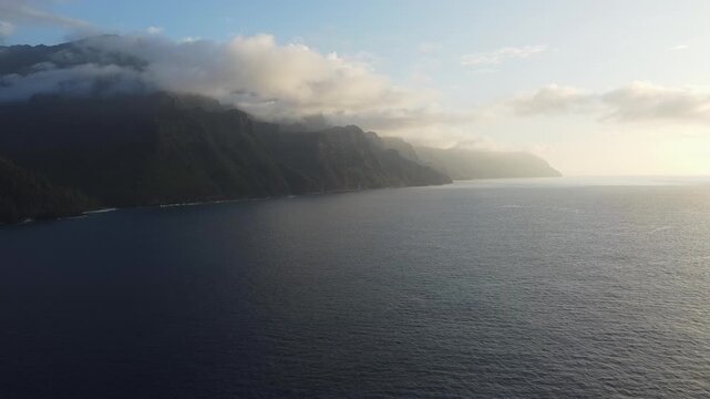 Aerial drone view of the Na Pali Coast cliffs with clouds over Kauai, Hawaii