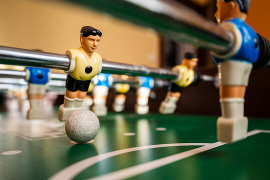 Close-up of table football player controlling the ball on a foosball table, symbolizing competition, teamwork and indoor entertainment with shallow depth of field.