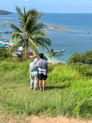 Fototapeta premium A couple enjoying a holiday atop a hill gazes out at the open sea off the coast of Teluk Tamiang, South Kalimantan