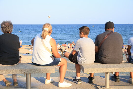 Personas sentadas en un banco frente al mar en un paseo mar&iacute;timo
