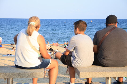 Personas sentadas en un banco frente al mar en un paseo mar&iacute;timo