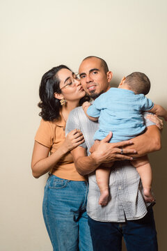Mother kissing father holding baby portraying family bonding