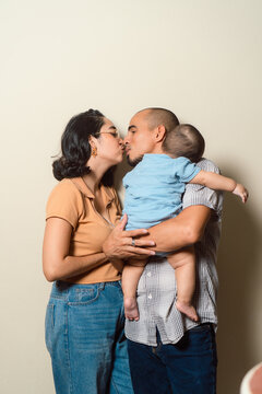 Parents kissing holding baby representing family love