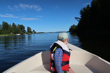 Fototapeta premium 4 Year Old Boy Rowing a Small Boat on Calm Water Near Höllviken, Sweden Summer Adventure