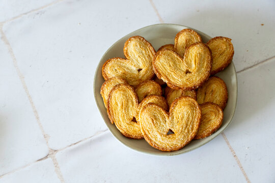 White ceramic plate of Palmiers cookies on a tile countertop 
