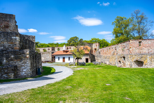 Visitors walk through the Boskovice Castle ruins in Czechia on a sunny day. The stone walls and grassy area invite exploration and discovery of history.