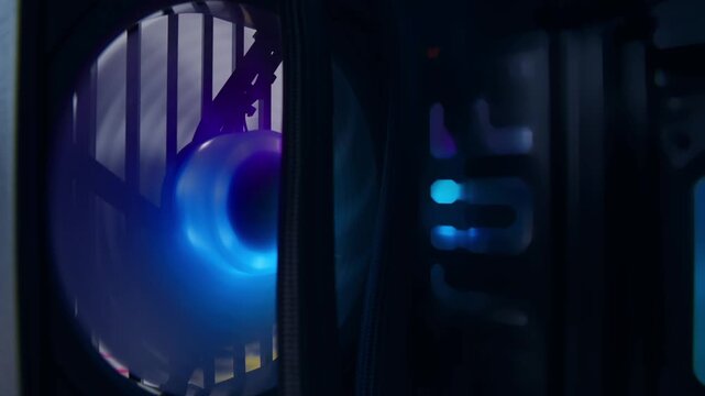 Extreme close-up of the colorful fans spinning on the computer's case illuminated by rainbow LED lights