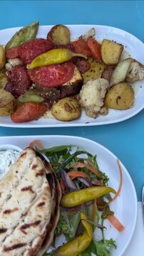 Traditional Greek meal with gyros, roasted potatoes, tzatziki sauce, grilled lamb with feta cheese and grilled vegetables served on table