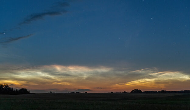 Glowing Noctilucent Clouds Above a Rural Landscape Before Sunrise