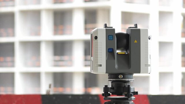 3D laser scanner on a construction site close-up of geologic measurements. Construction panels and red accents form the backdrop. Shallow depth of field blurs the background