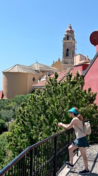Cervo, liguria, italy. June 22, 2025. Revealing view of cervo in liguria, italy. A young female tourist leaning on a railing admiring the panoramic view of the sea