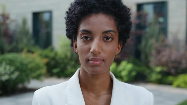Headshot confident serious African American business woman thinking looking at camera in city. Peaceful relaxed pretty ethnic girl student female businesswoman look posing outdoors real estate trader