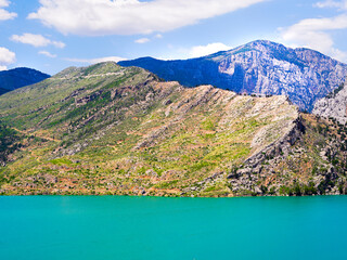 Obraz premium Beautiful scenic view of turquoise water lake and rocky mountains under a blue sky