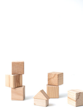 Wooden geometric blocks and small house stacked on vertical white background with copy space