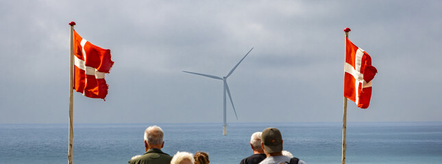 Danish flags and wind turbine by the sea, people watching © Taljat