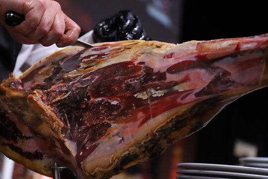 maestro del corte de jam&oacute;n limpiando un jam&oacute;n ib&eacute;rico de la capa exterior