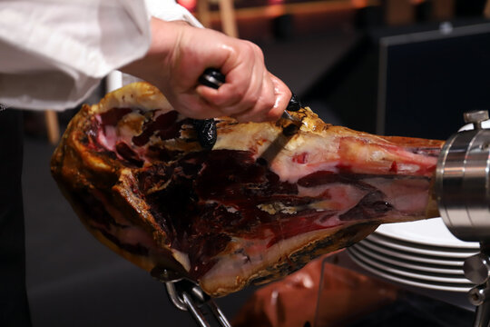 experto jamonero manipulando un jam&oacute;n ib&eacute;rico quit&aacute;ndole la costra exterior