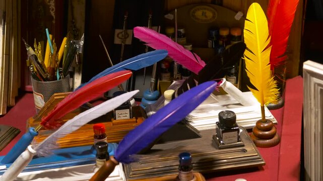 Colorful antique quill pens and inkwells displayed in a shop. Various old-fashioned feather pens and calligraphy sets displayed on a wooden shelf in a vintage souvenir shop