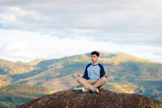 Brazilian man meditating on a rock in nature, representing mindfulness, inner peace, wellness, mental health, relaxation, and a balanced lifestyle.